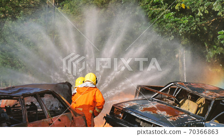 Firefighter fighting with flame using fire hose chemical water foam spray engine 70366863