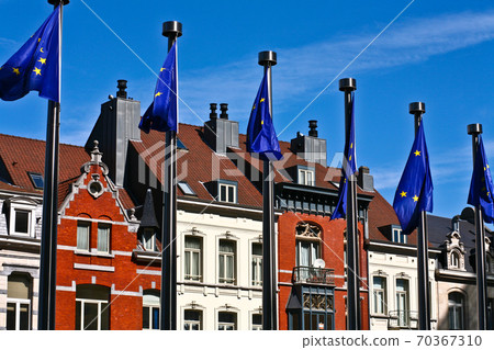Flags in front of the Berlaymont building in Brussels and old typical houses 70367310