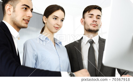 Group of business people discussing questions at meeting in office. Colleagues working with computer at workplace Group of business people discussing questions at meeting in office. Colleagues working with computer at workplace 70367918