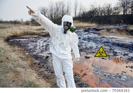 Scientist exploring the territory, emission area, polluted water, man in protective suit installing warning signs Scientist exploring the territory, emission area, polluted water, man in protective suit installing warning signs 70368161