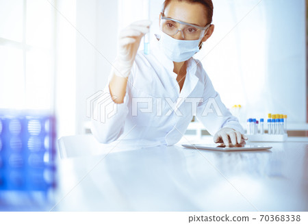 Female laboratory assistant analyzing test tube with blue liquid. Medicine, health care and researching concept 70368338