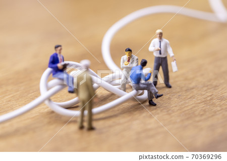Businessmen discussing tangled cables 70369296