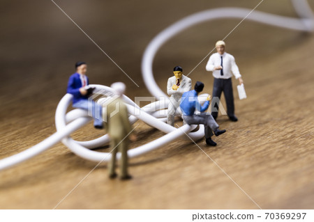 Businessmen discussing tangled cables 70369297