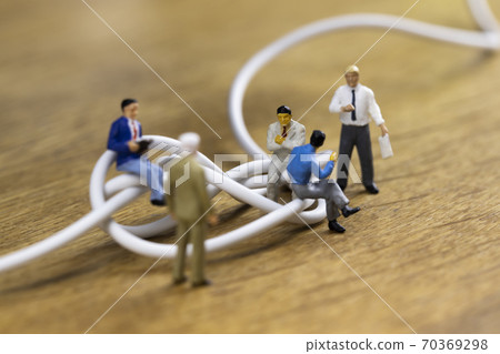 Businessmen discussing tangled cables 70369298