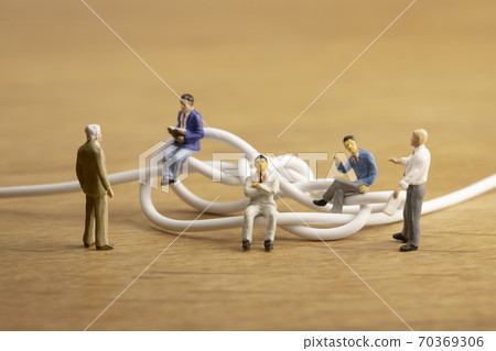 Businessmen discussing tangled cables Businessmen discussing tangled cables 70369306