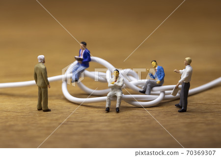Businessmen discussing tangled cables Businessmen discussing tangled cables 70369307