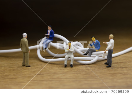 Businessmen discussing tangled cables 70369309