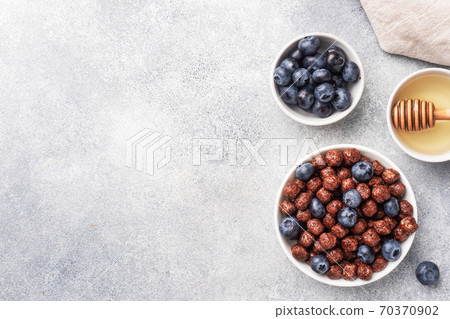 Chocolate flakes made from natural cereals with fresh blueberries, honey and milk. The concept of a healthy wholesome Breakfast. copy space Grey concrete background 70370902