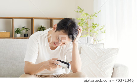 一個人在客廳裡玩電子遊戲 70371346