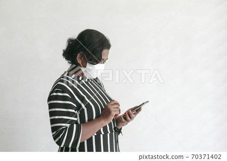 Businesswoman wearing face mask surfing on her cellphone Businesswoman wearing face mask surfing on her cellphone 70371402