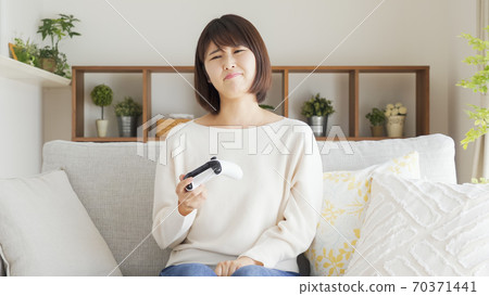 Woman playing video games in the living room Woman playing video games in the living room 70371441