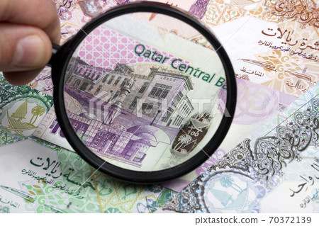Qatari riyal in a magnifying glass a business background 70372139