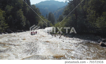 A team of rafters on a boat rowing oars. A team of rafters on a boat rowing oars. 70372916