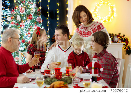 Family with kids having Christmas dinner at tree 70376042