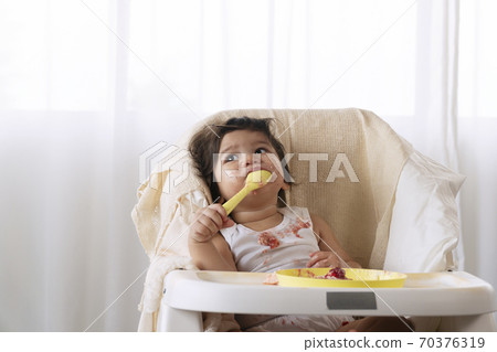 Little cute child celebrating her first birthday with cake at home. 70376319