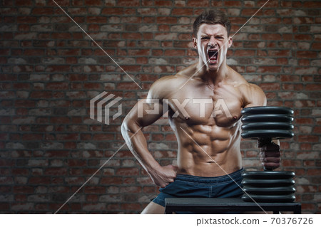 Bodybuilder strong man pumping up abs muscles 70376726