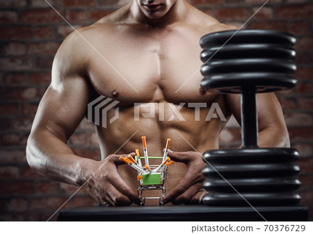 Bodybuilder strong man pumping up abs muscles Bodybuilder strong man pumping up abs muscles 70376729