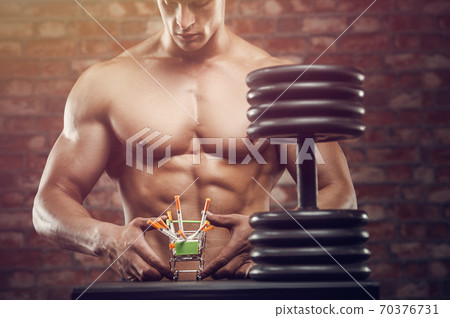 Bodybuilder strong man pumping up abs muscles 70376731