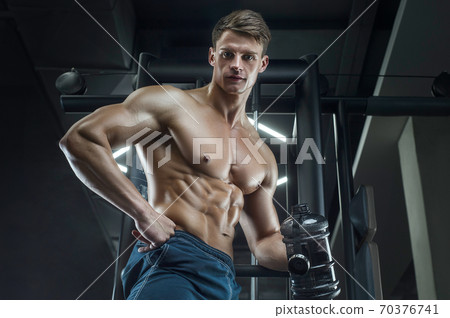 Bodybuilder drinking water after fitness workout. 70376741