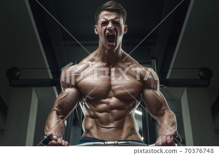 Bodybuilder strong man pumping up biceps muscles 70376748