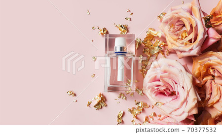 Perfume transparent white bottle, pink golden roses and pieces of golden paper on light pink background. Top view, Luxury flat lay, copy space. Perfume transparent white bottle, pink golden roses and pieces of golden paper on light pink background. Top view, Luxury flat lay, copy space. 70377532
