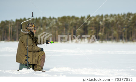 fisherman fishing on a winter lake. winter sport fishing fisherman fishing on a winter lake. winter sport fishing 70377855