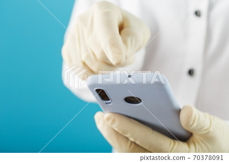 Smartphone in rubber gloves holding and using the touch screen of the smartphone, the concept of protection against the spread of viral infections. Smartphone in rubber gloves holding and using the touch screen of the smartphone, the concept of protection against the spread of viral infections. 70378091
