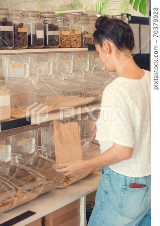 Young woman shopping in zero waste plastic free store with reusable mesh bag. Low waste lifestyle. Sustainable eco lifestyle 70379928