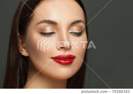 Beautiful woman face with elegant makeup close up. Red lips, golden eyeshadow and black eyeliner Beautiful woman face with elegant makeup close up. Red lips, golden eyeshadow and black eyeliner 70380383