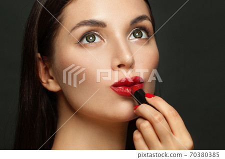 Dreamy woman face with red glossy lips and lipstick on black background 70380385