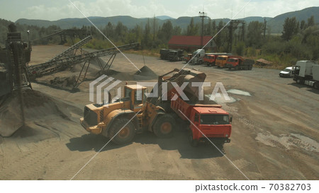 Yellow excavator pours coal into a truck. Yellow excavator pours coal into a truck. 70382703