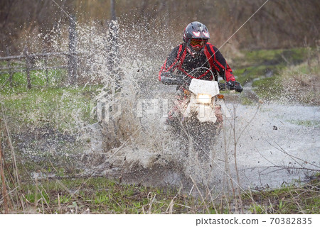 Motorcross rider racing in flooded wood 70382835