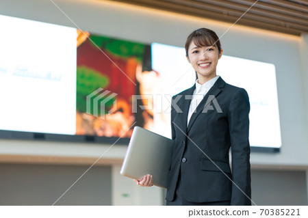 站立與在大視覺前面的一台個人計算機的一個年輕女商人 70385221