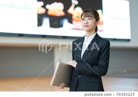 站立與在大視覺前面的一台個人計算機的一個年輕女商人 站立與在大視覺前面的一台個人計算機的一個年輕女商人 70385225
