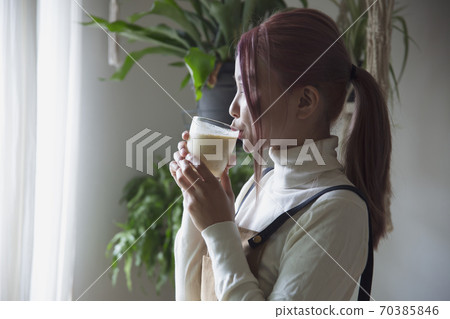 Image photo of a young woman drinking a homemade juice smoothie by the window 70385846