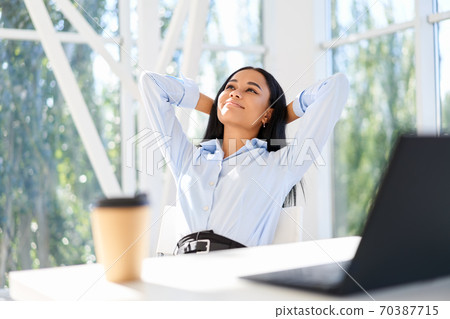 Attractive african american businesswoman resting in modern office enjoying free time Attractive african american businesswoman resting in modern office enjoying free time 70387715