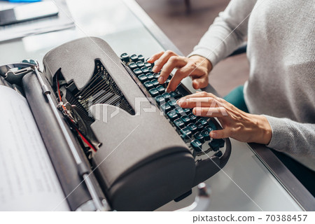 Female fingers on the keys of the typewriter type text. 70388457