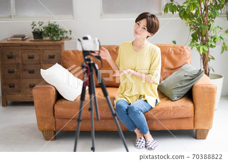 A woman recording a video in front of the camera 70388822