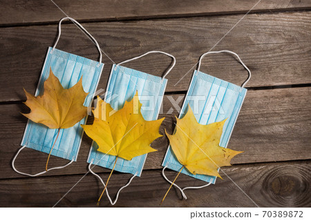.Autumn fallen leaves and medical masks on wooden background. 70389872