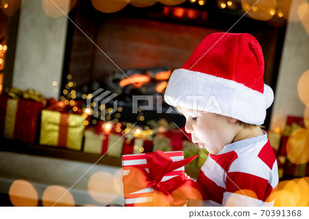 Surprised child opening Christmas gift Surprised child opening Christmas gift 70391368
