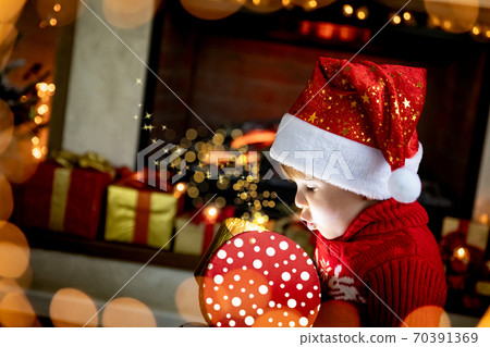 Surprised child opening Christmas gift Surprised child opening Christmas gift 70391369