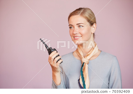 Flight Attendant Speaking to Portable Radio Flight Attendant Speaking to Portable Radio 70392409