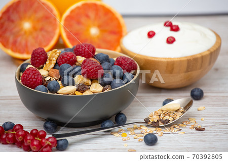 Bio Fruit Blueberry in bowl wood and Natural yogurt, kiwi, Raspberry, and nuts for health and diet with vitamin c in close-up on the wood table. 70392805