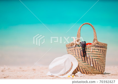 Beach accessories - straw bag, hat and unglasses on the beach Beach accessories - straw bag, hat and unglasses on the beach 70392827