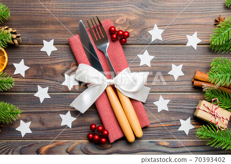 Top view of utensils on festive napkin on wooden background. Christmas decorations with dried fruits and cinnamon. Close up of New year dinner concept 70393402