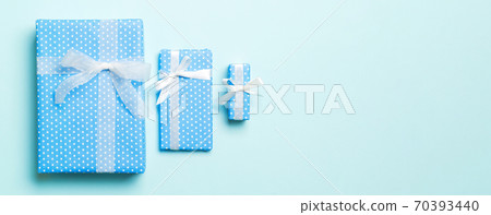 wrapped Christmas or other holiday handmade present in paper with white ribbon on blue background. Present box, decoration of gift on colored table, top view 70393440