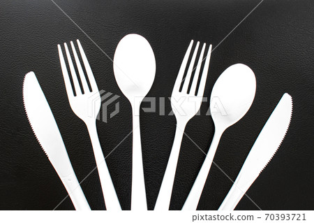 Single use white plastic cutlery on a leather background. Concept Single use white plastic cutlery on a leather background. Concept 70393721