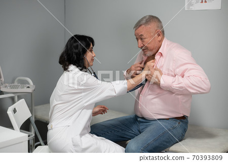 A doctor with a stethoscope listening to patients heartbeat A doctor with a stethoscope listening to patients heartbeat 70393809