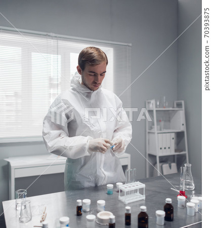 A researcher doing a chemical test in the laboratory, mixing some substances 70393875