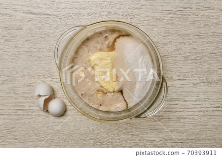 A mixture of milk, eggs, butter, sugar, salt, baking powder, vanillin, and yeast in a clear glass saucepan.  70393911